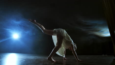 Moderner-Tanz:-Eine-Frau-Im-Weißen-Kleid-Tanzt-Ein-Modernes-Ballett-Und-Springt-Auf-Der-Bühne-Mit-Rauch-Im-Blauen-Scheinwerferlicht.